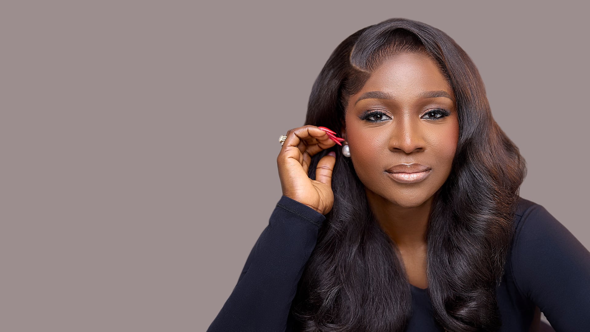 La'blinks model showcasing glossy voluminous wavy hair, hand gracefully touching her pearl earring